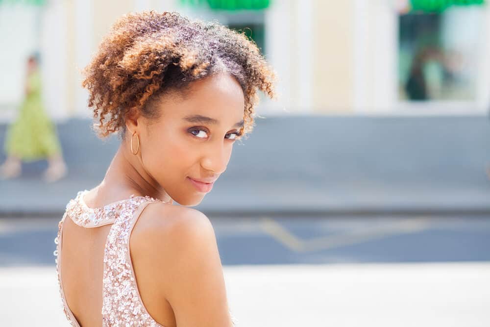 Beautiful African American female with ombre afro hair wearing gold hoop earrings and pink lipstick.