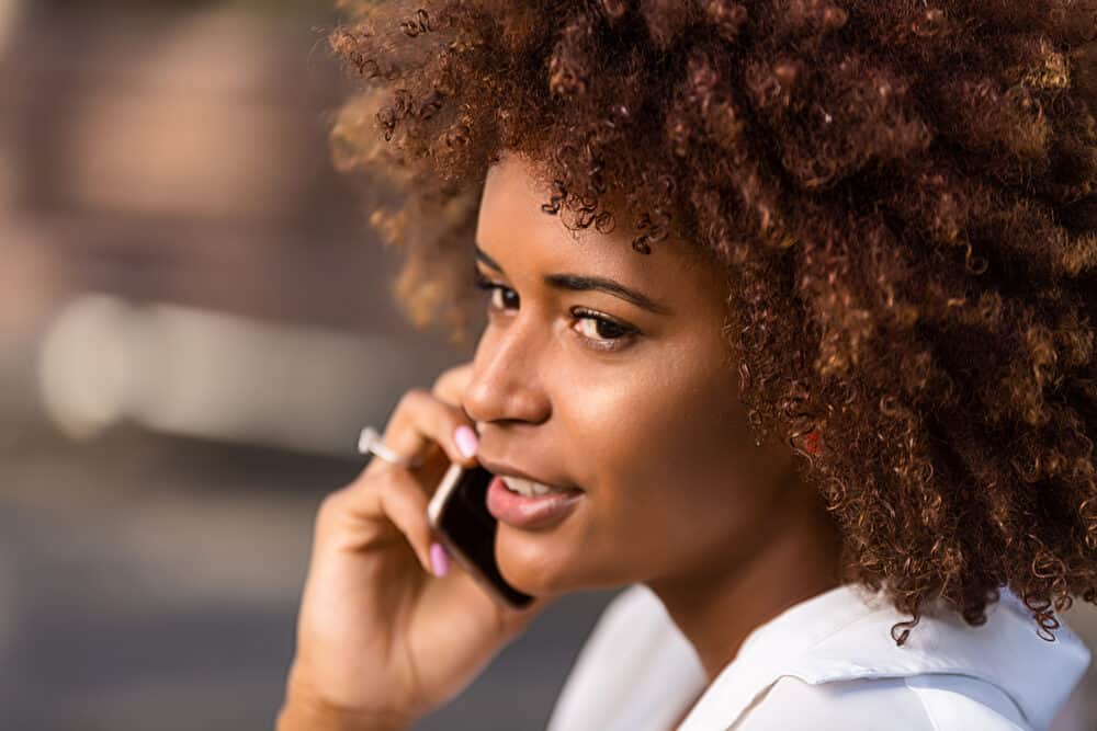 African female with pink fingernail polish and a curly hairstyle