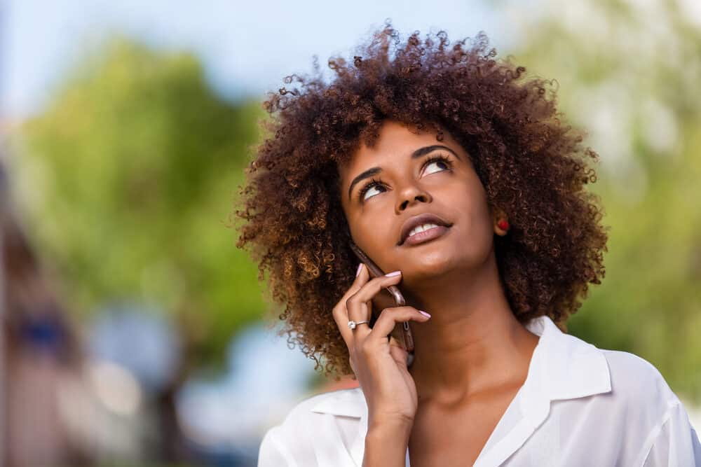 Woman looking into the sky wondering with brown curls and a large diamond ring on her right hand