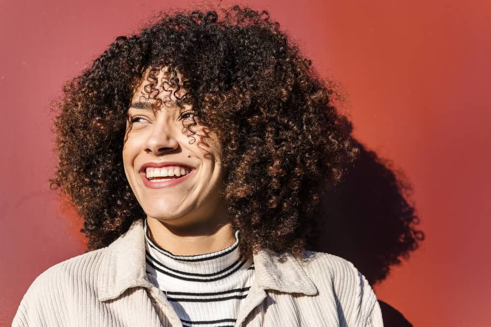 Latina female with beautiful finger coils wearing winter attire on a sunny, windy day.