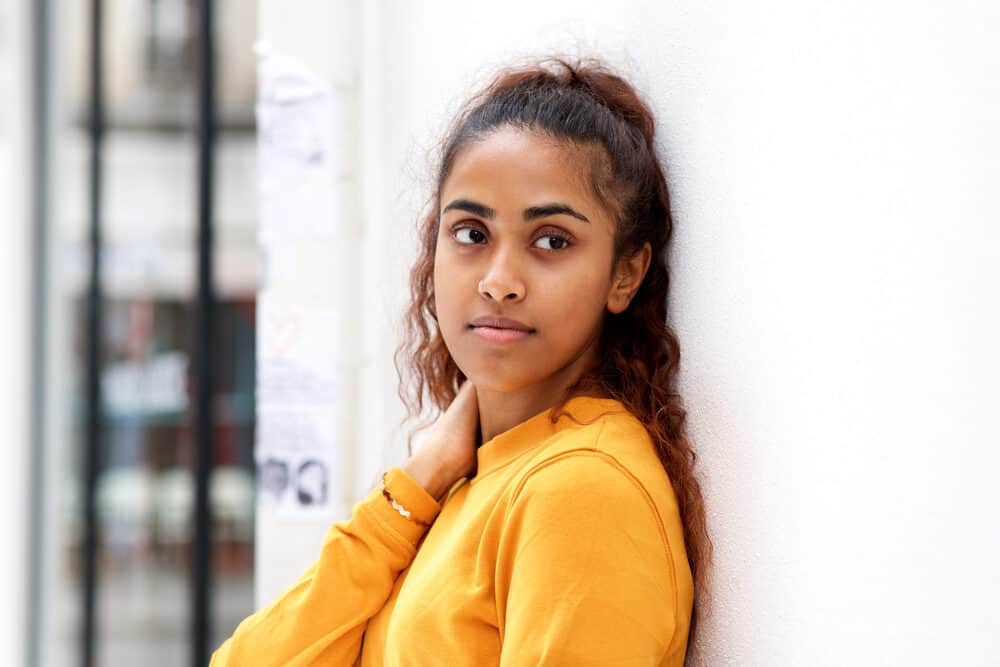 Beautiful Indian woman wearing an orange shirt and brown wavy hair after leaving her hair stylist.