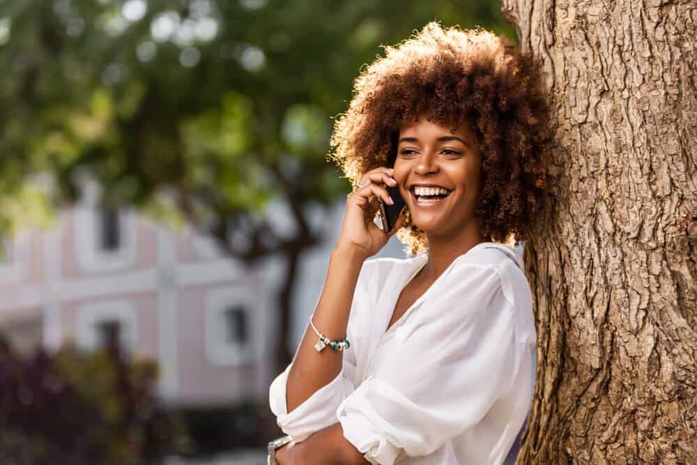 Black girl talking on the phone, asking her friend, can I remove toner from my hair