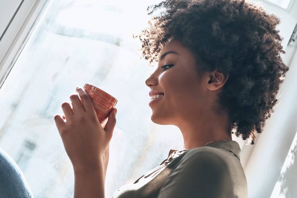 Women with 4c hair type having a cup of coffee during an early summer morning