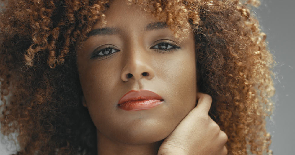 Beautiful black lady with blonde and brown curls looking directly into the camera