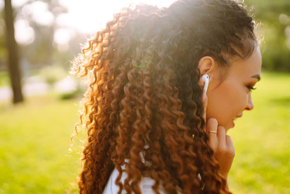 African American girl with curly hair follicles wearing Apple air pods