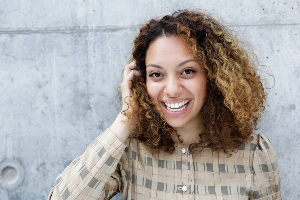 Cute mixed-race girl type 3c curls wearing a green, brown, and badge shirt