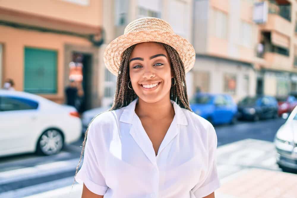 A young African American woman with braids standing outside on a sunny day in the summer.
