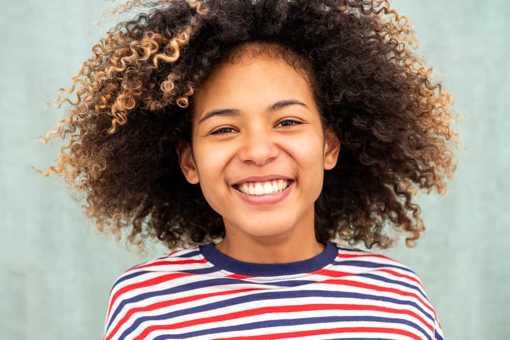 Light-skinned female wearing a red, white, and blue stripped sweater with blonde, gold, and brown hair.