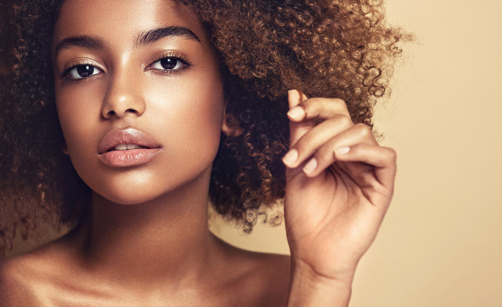 Cute black female showing off brown curls and pink lipstick.