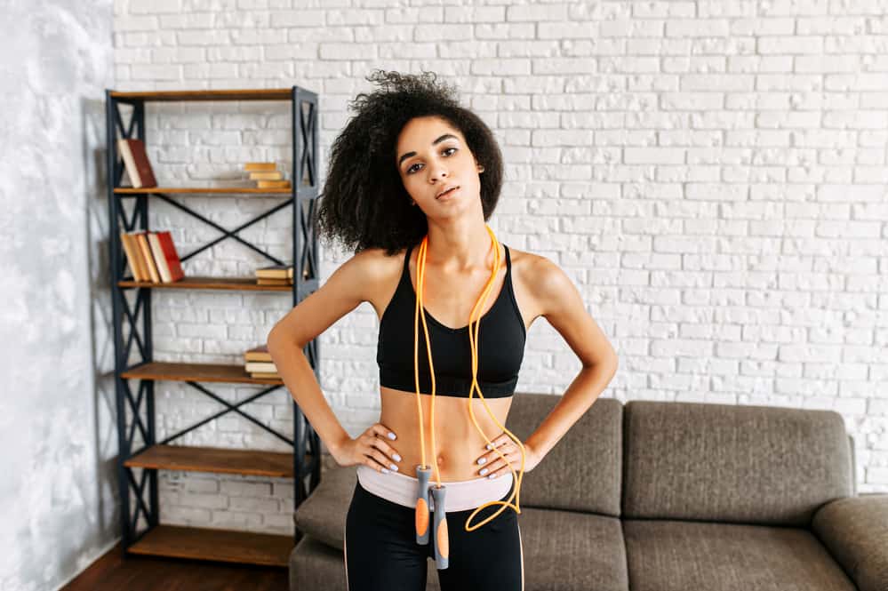 A beautiful woman with curly hair getting ready to jump rope at home.