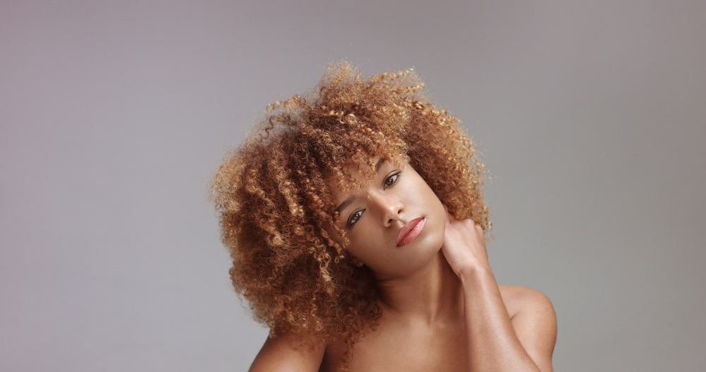 Mixed race black woman wearing red lipstick and black eyeshadow with her hand behind her neck