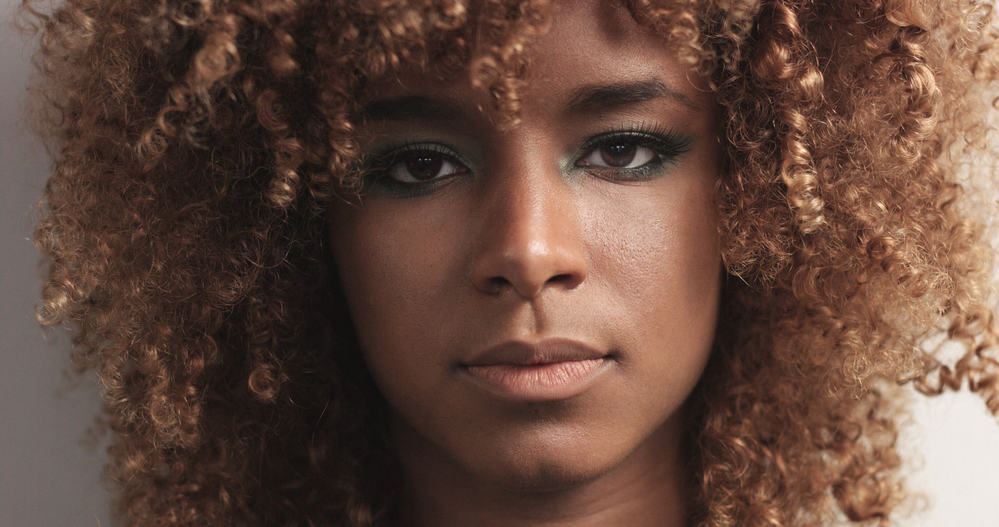 Close-up of light-skinned black girl with a curly texture and blue eyeshadow to compliment her style