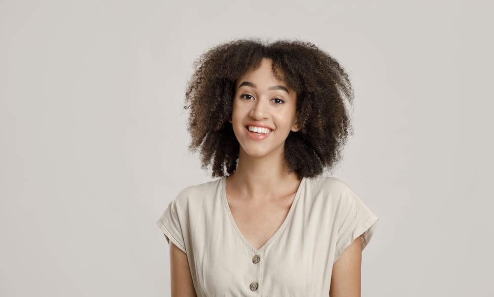 Millennial African American female with curly curtain bangs wearing a badge shirt