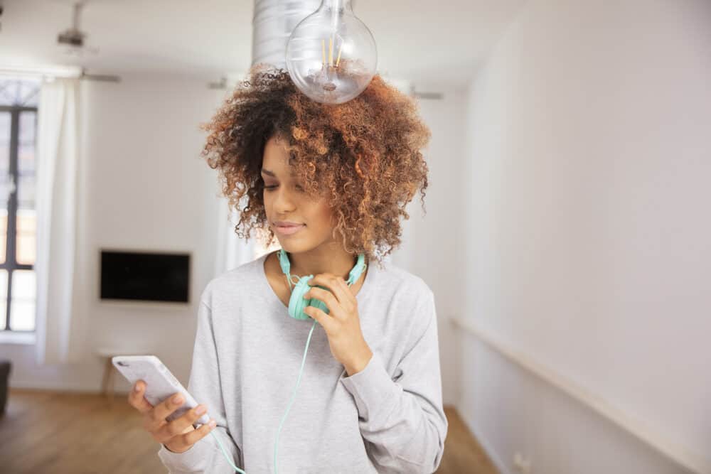 African American female wearing a gray sweatshirt with ombre naturally curly hair strands