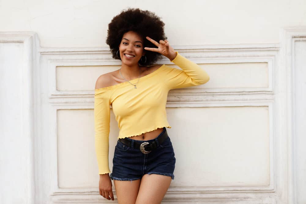 Cute African American women with virgin hair wearing a brassy yellow shirt and blue jean shorts