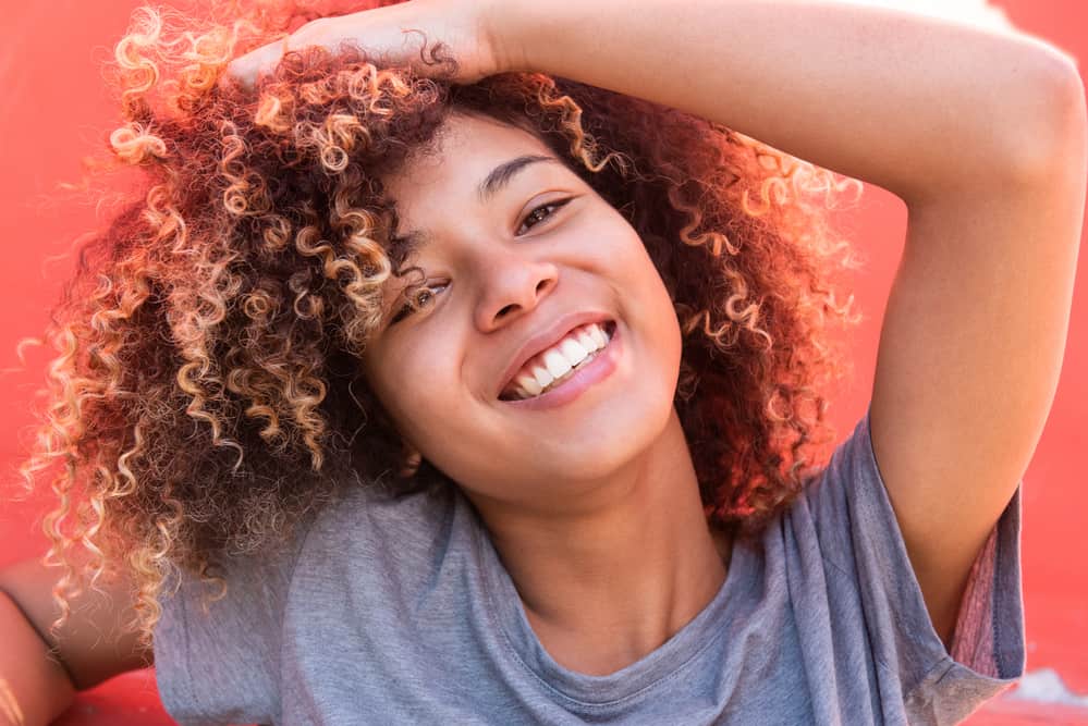 Beautiful African American female hair care enthusiast with naturally curly hair wearing a gray t-shirt.