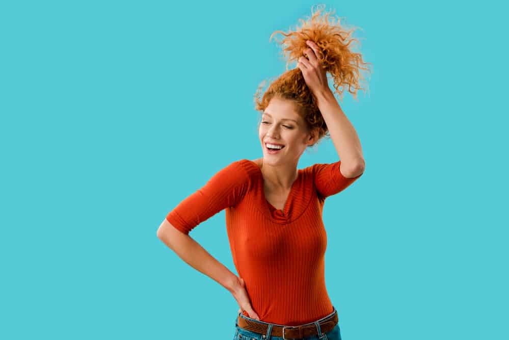 European female with a pineapple hairstyle on wavy curly hair strands.