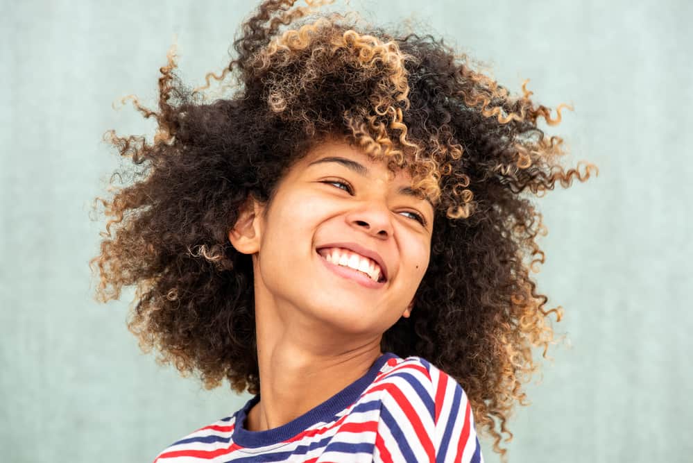 Women with curly natural hair looking away while smiling at a joke.