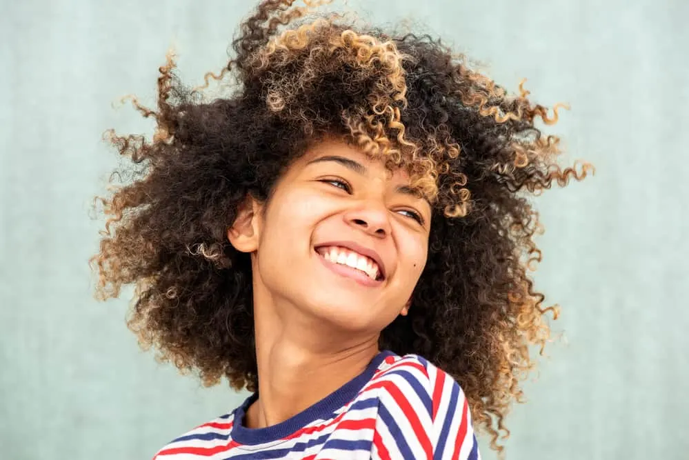 Women with curly natural hair looking away while smiling at a joke.