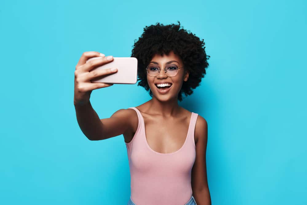 Lady wearing a pink shirt while taking a selfie with her mobile phone