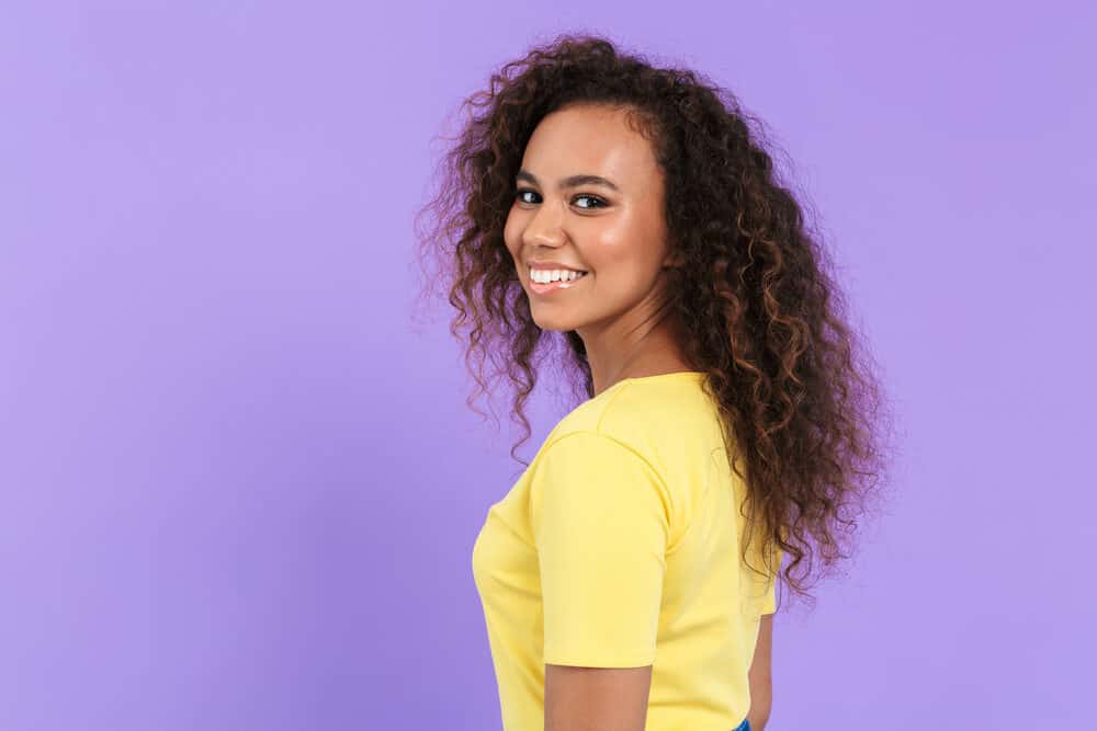 Black girl with dark hair after removing purple toner from her curly hair strands