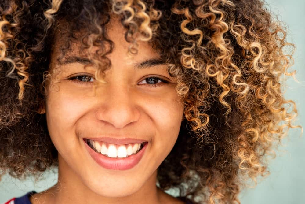 Beautiful female with curly hair brown and blonde hair wearing pink lipstick.