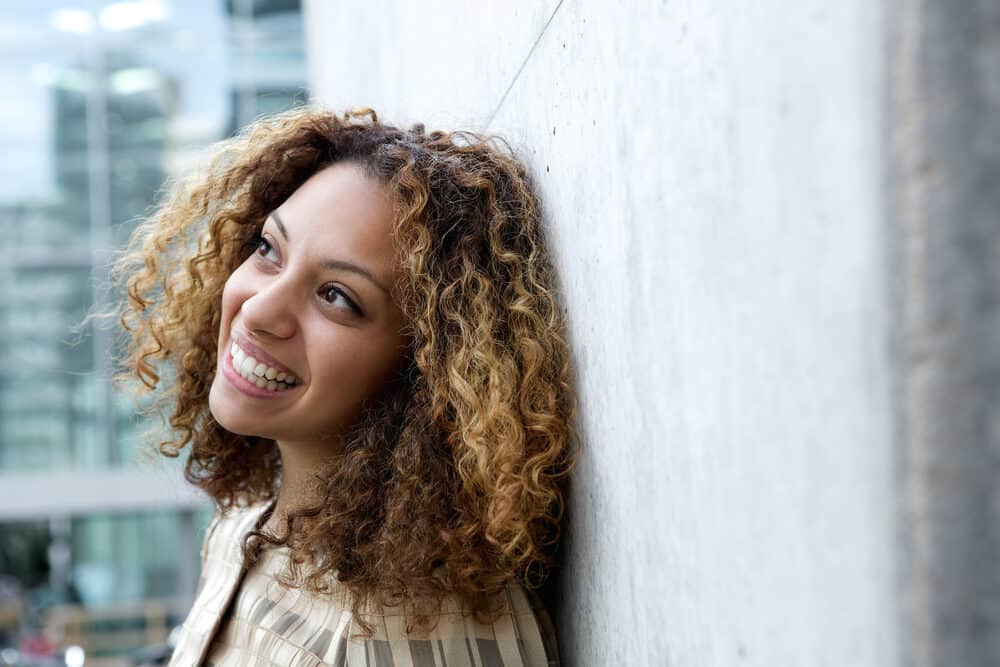 African American female wearing light and dark brown ombre hair follicles looking into the distance