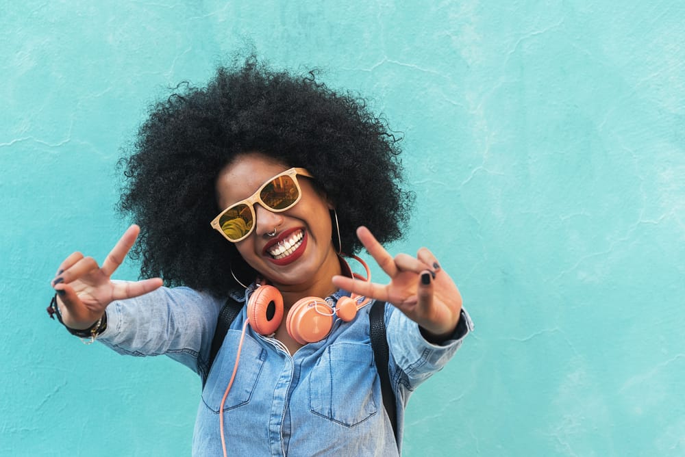 African-American girl with natural hair wearing a white t-shirt, blue jeans, and three necklaces.