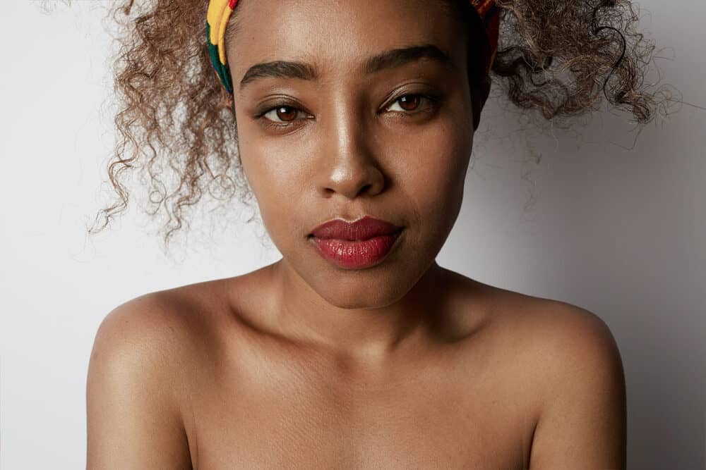 Close-up of a young African American girl with red lipstick and naturally curly hair.