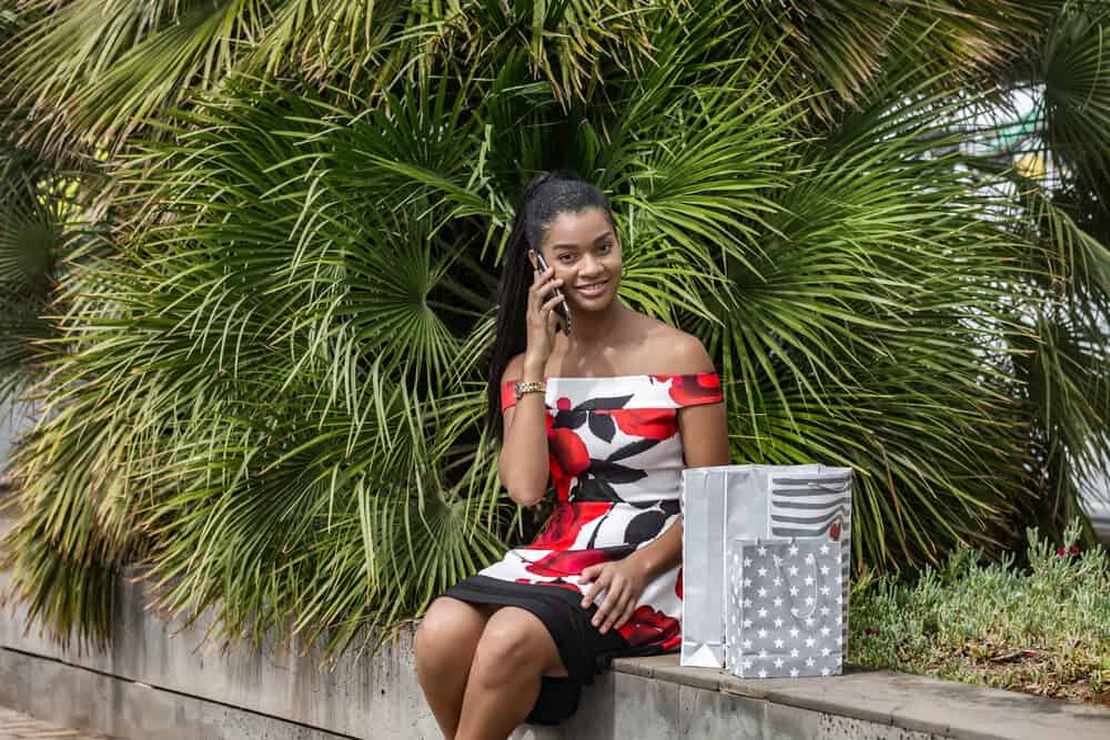 African American female wearing a multi-colored dress after purchasing several items during a shopping trip.