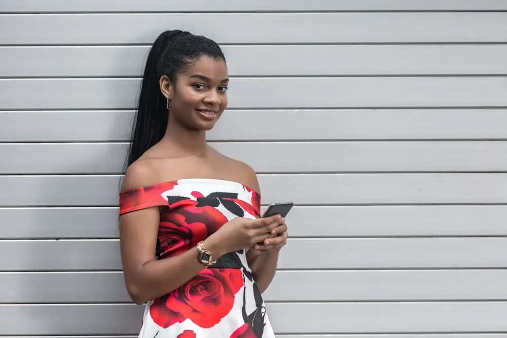 How To Do a Sleek Ponytail on Natural Hair (or Weave) Without Flyaways 2 Happy black girl with a mid-length ponytail secured with bobby pins browsing links on her cell phone.