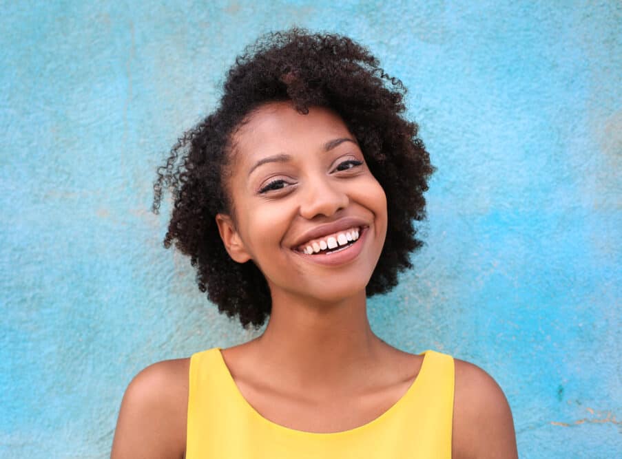 Cute black girl with curly precious hair wearing a yellow t-shirt.