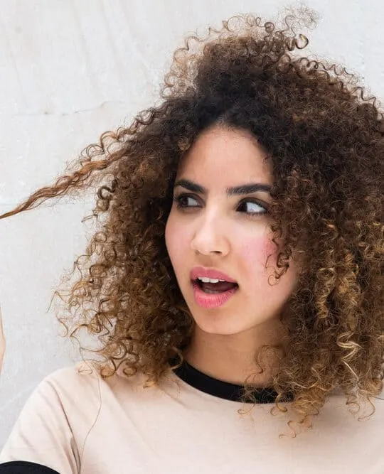 Black woman with type 3b curly hair holding her hair strand after using the squish to condish method with flax-seed gel.