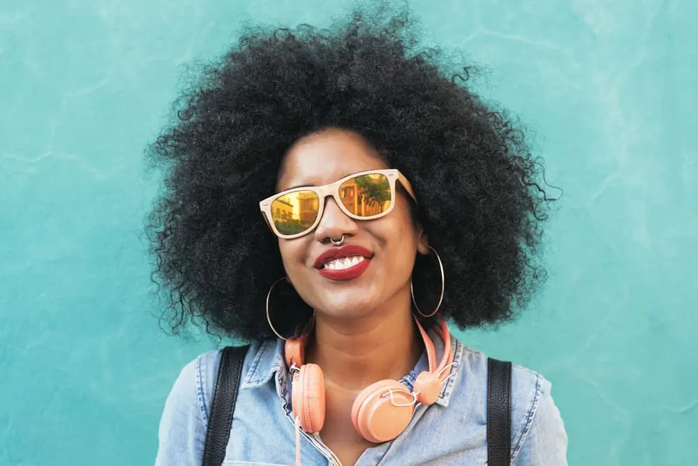 Is Suave Shampoo Good for Your Hair? What About Their Conditioner and Other Products? 5 Black lady with naturally curly 4c hair strands and hoop earrings with a huge smile on her face.