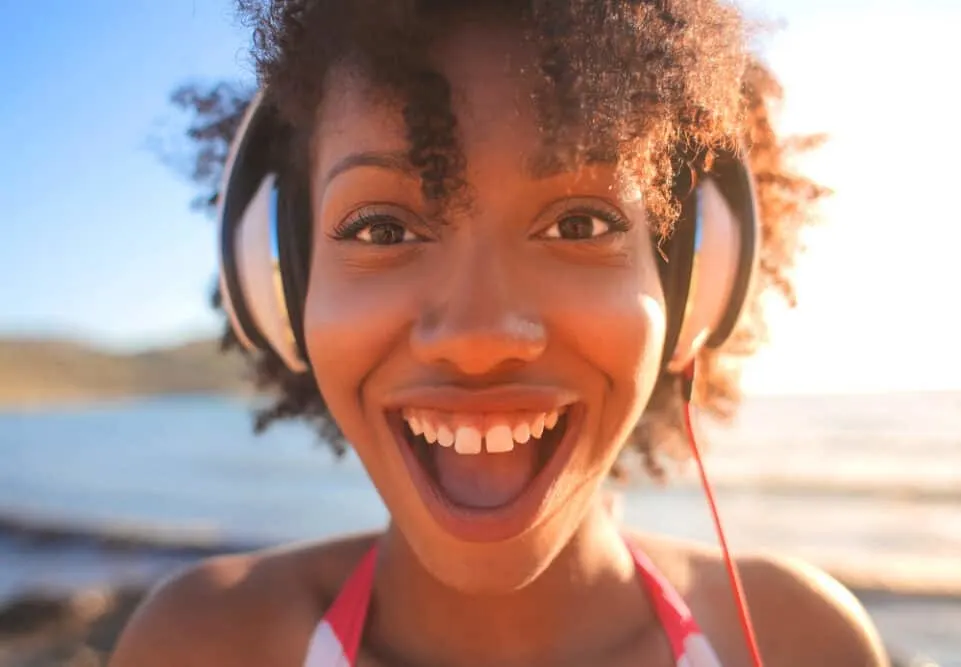 Girl wearing headphones on a sunny day with brown hair wearing a swimsuit.