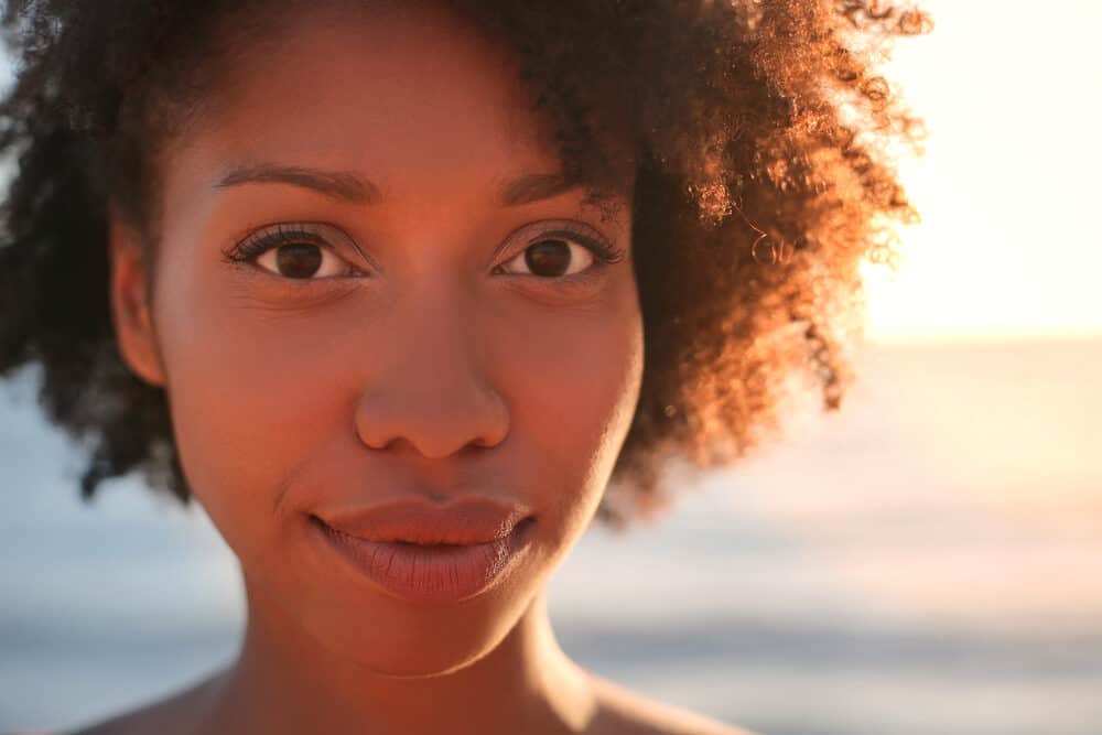 Close-up of black women trying to avoid dry and damaged hair standing outside on a sunny day.