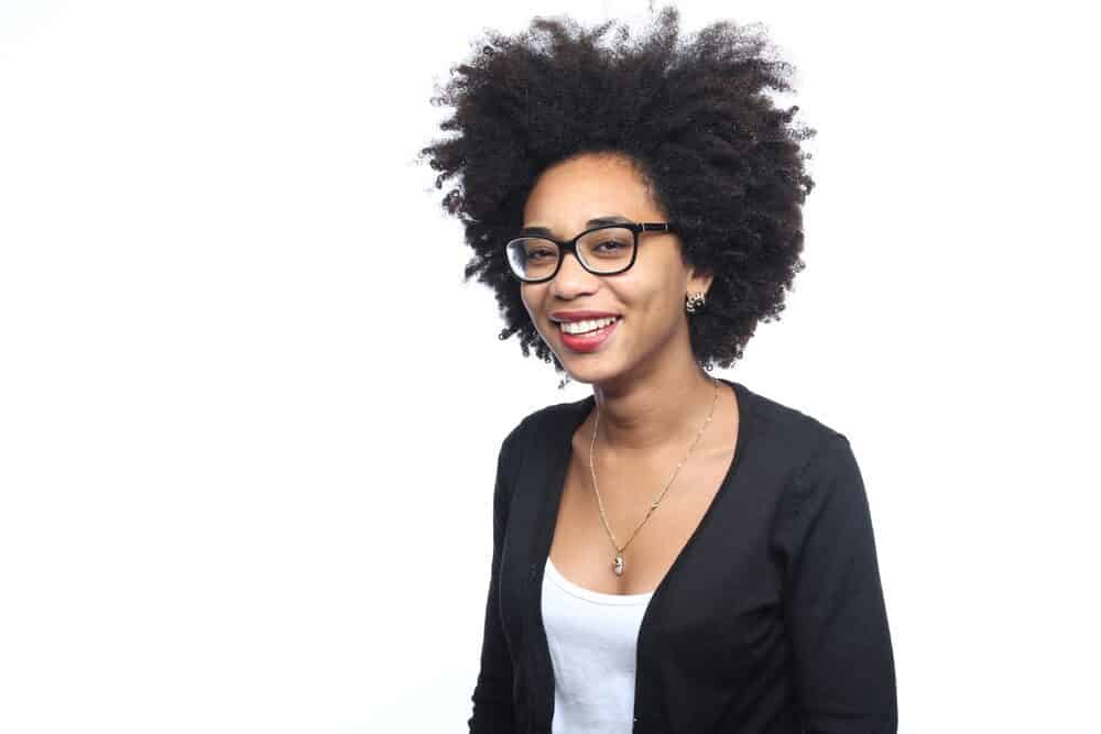 Black girl with beautiful natural curls wearing a long silver necklace and a black sweater.