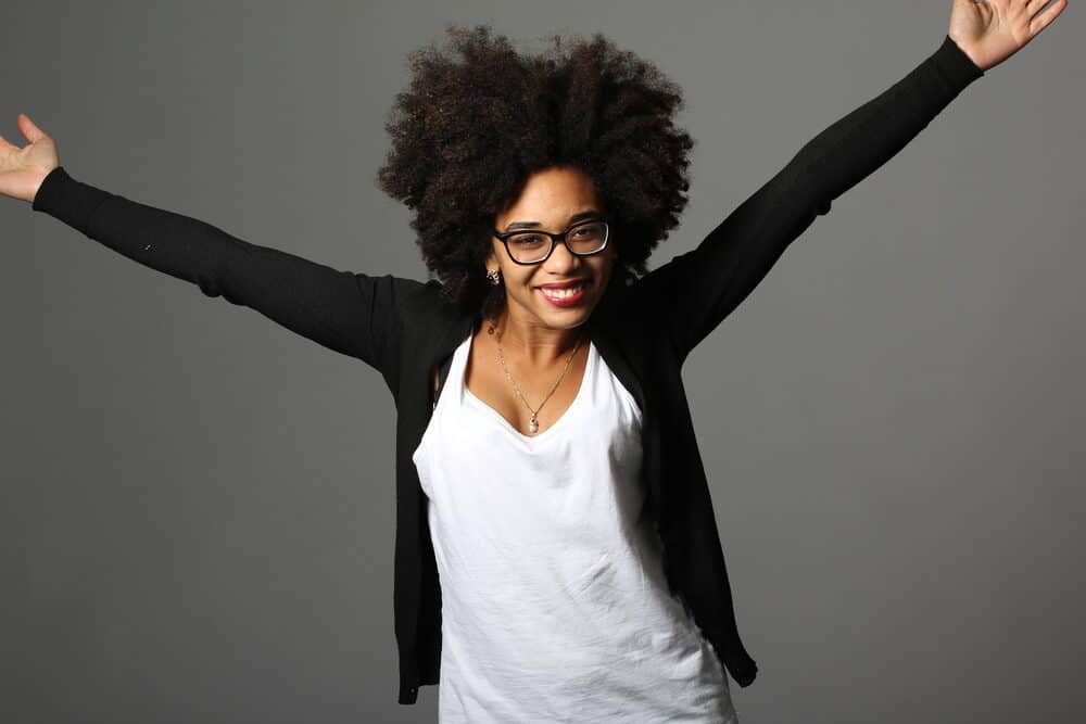 Black female with naturally curly hair strands in an afro style.