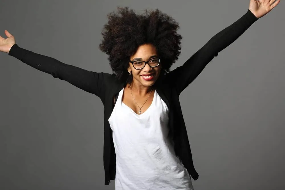 What is Coily Hair and How Do I Care for It? 14 Black female with naturally curly hair strands in an afro style.