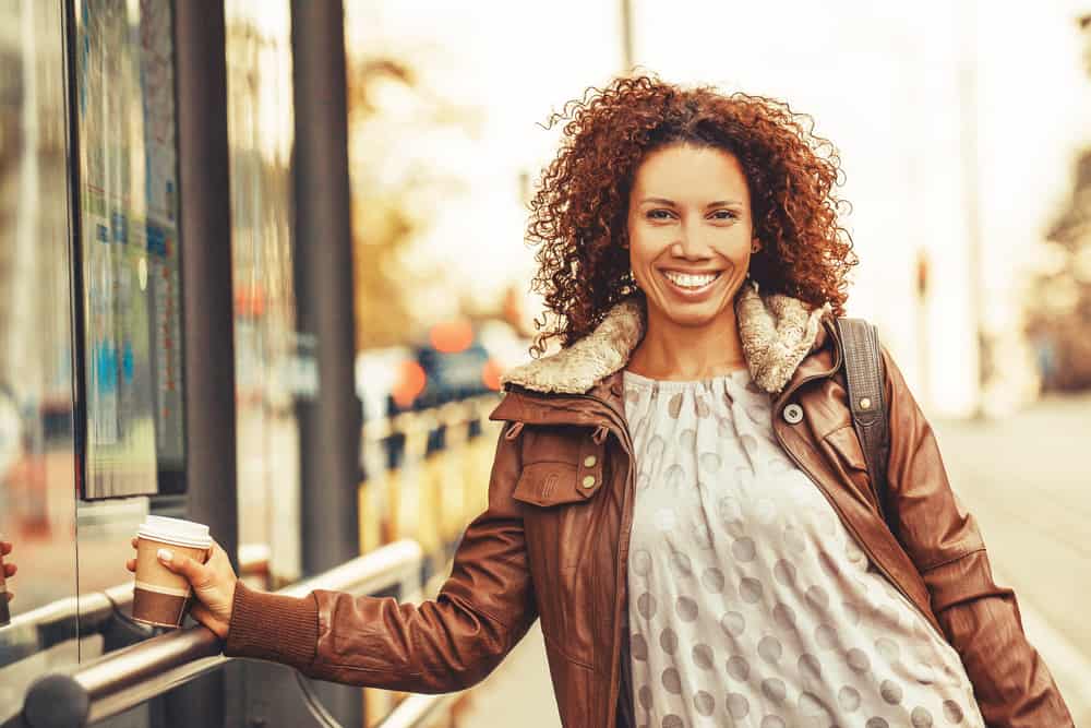  Ragazza carina in piedi fuori in attesa sul bus in una fresca giornata autunnale.