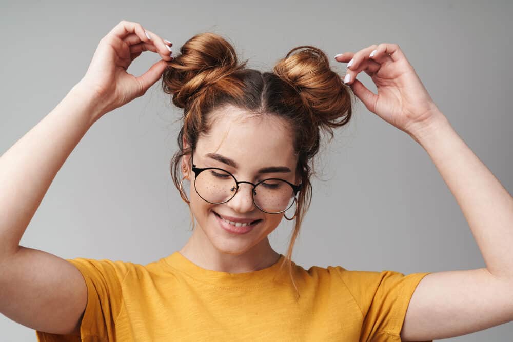 Cute lady with freckles wearing one of many double bun protective hairstyles for white hair