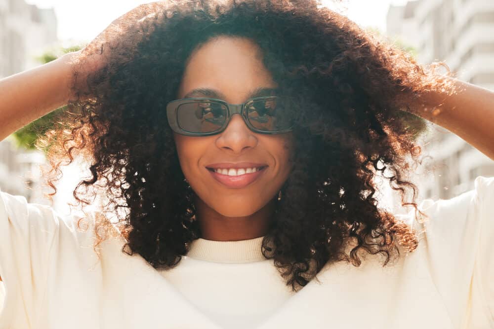 Black woman wearing Indian hair with a deep curly hair texture blended with her own hair.