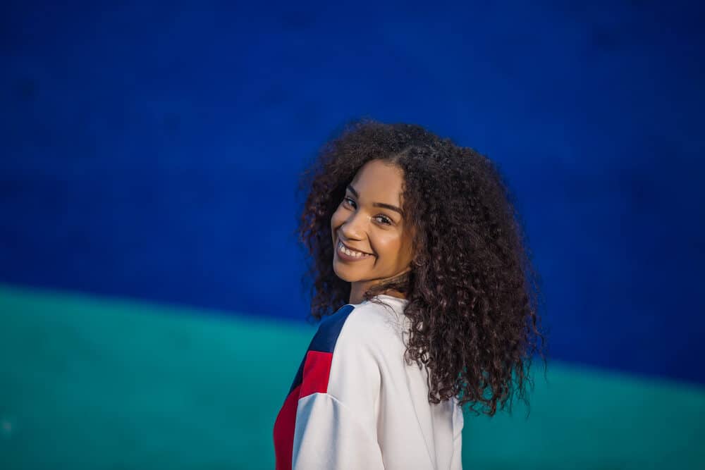 Cute black girl smiling wearing a sleek and chic look with type 3A natural curl pattern.