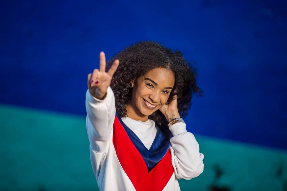 Cute black girl wearing a red, white, and blue sweatshirt with curly hair weave blended with her naturally curly hair.