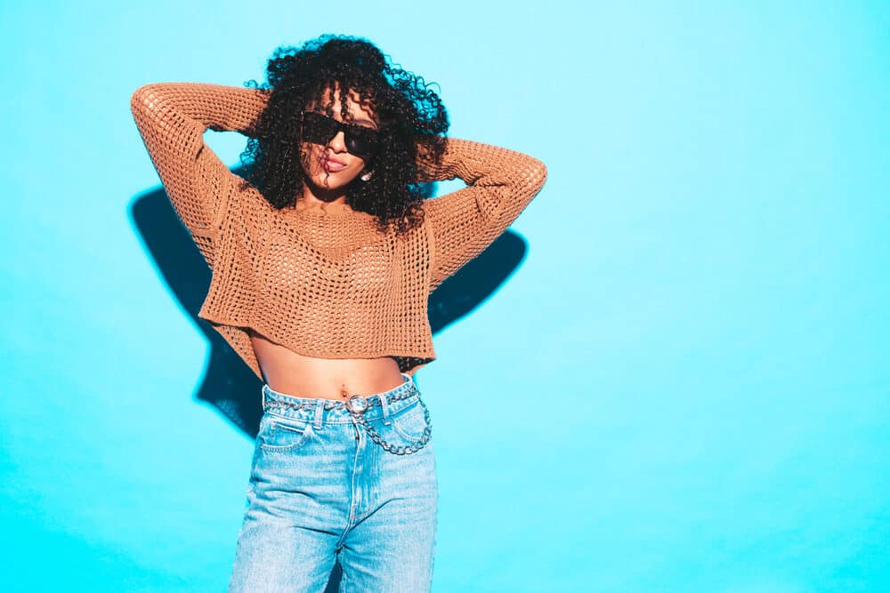 A cute black lady wearing Malaysian hair that looks like kinky curly hair strands with tight curls.