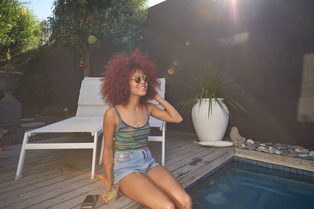 Adult female dipping her feet in the villa while wearing red curls.