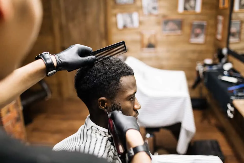 Barber using clippers to cut the longer hair around the base of his client's head.