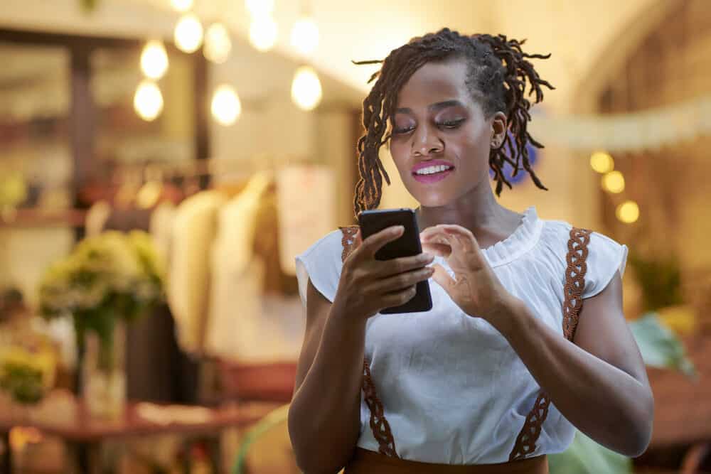 Cute woman with curly locks using her mobile phone at a department store.