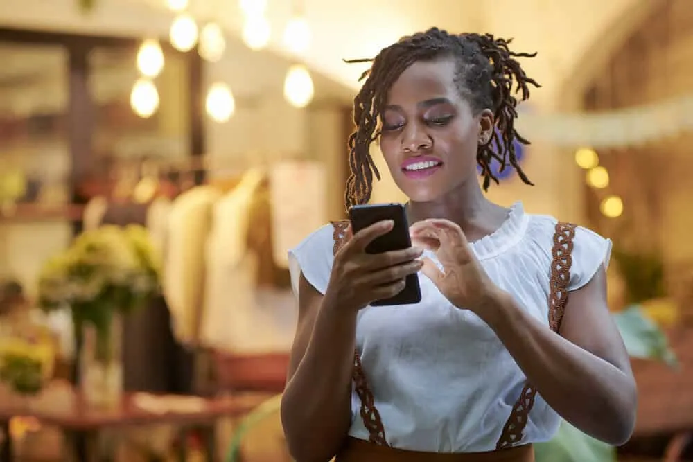 Are Dreads Dirty Hair? Why Do Dreadlocks Look Dirty? 3 Cute woman with curly locks using her mobile phone at a department store.