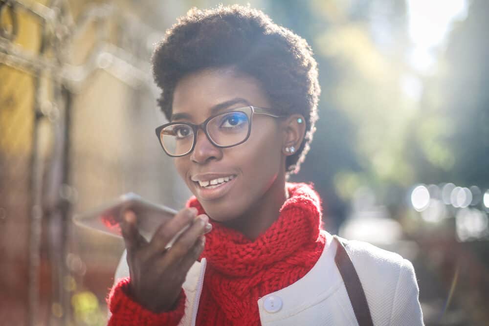 Women with z pattern natural hair with a brown leather bag, red sweater, and a white suit jacket.